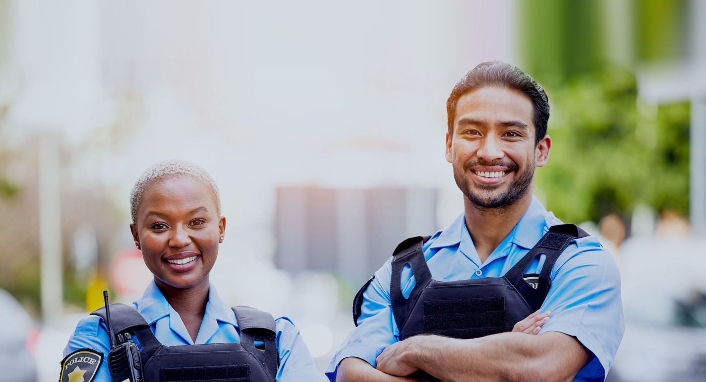 Two smiling police officers in uniform standing with their arms crossed